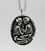 Silver necklace with a pendant featuring two interlocking skeletons on a light gray background